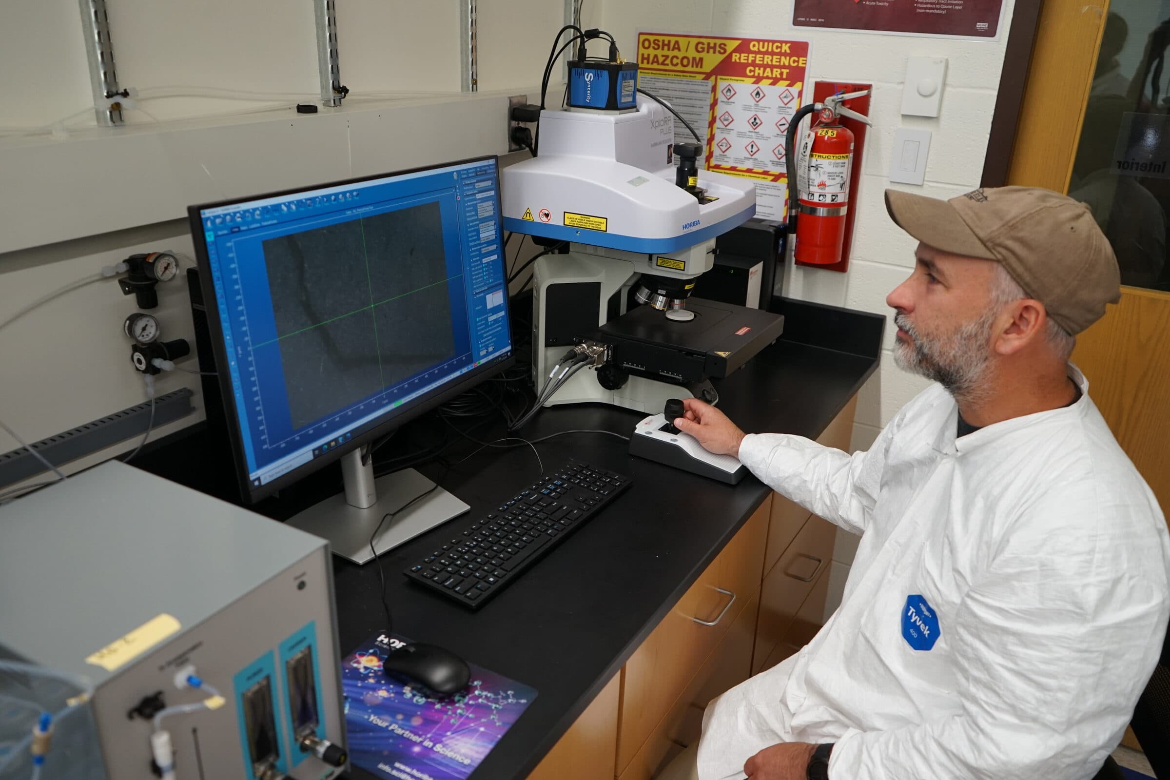 USGS scientist operating a Raman microscope beside a computer monitor