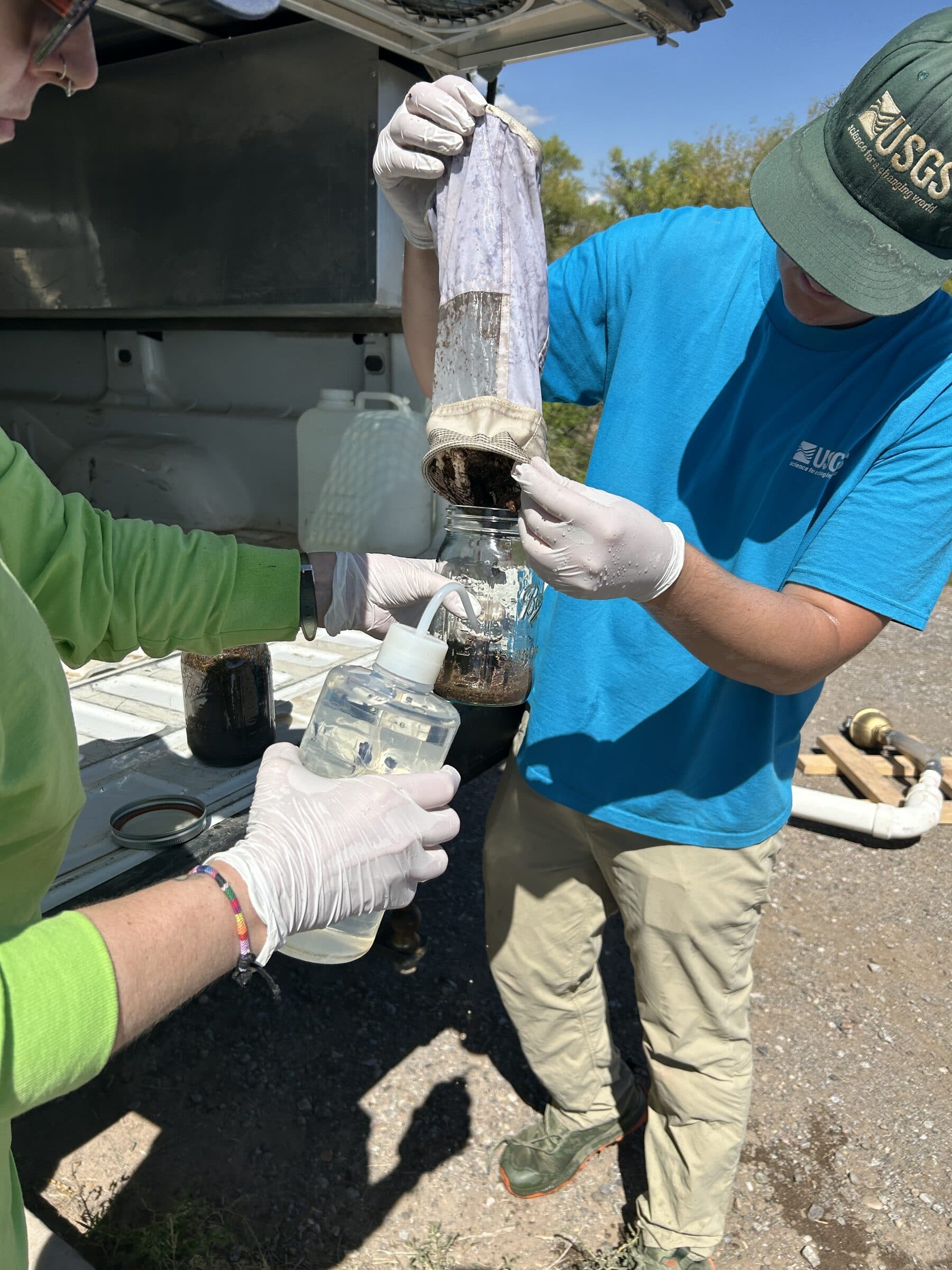 Gloved researchers transferring a water sample through microplastics collection equipment